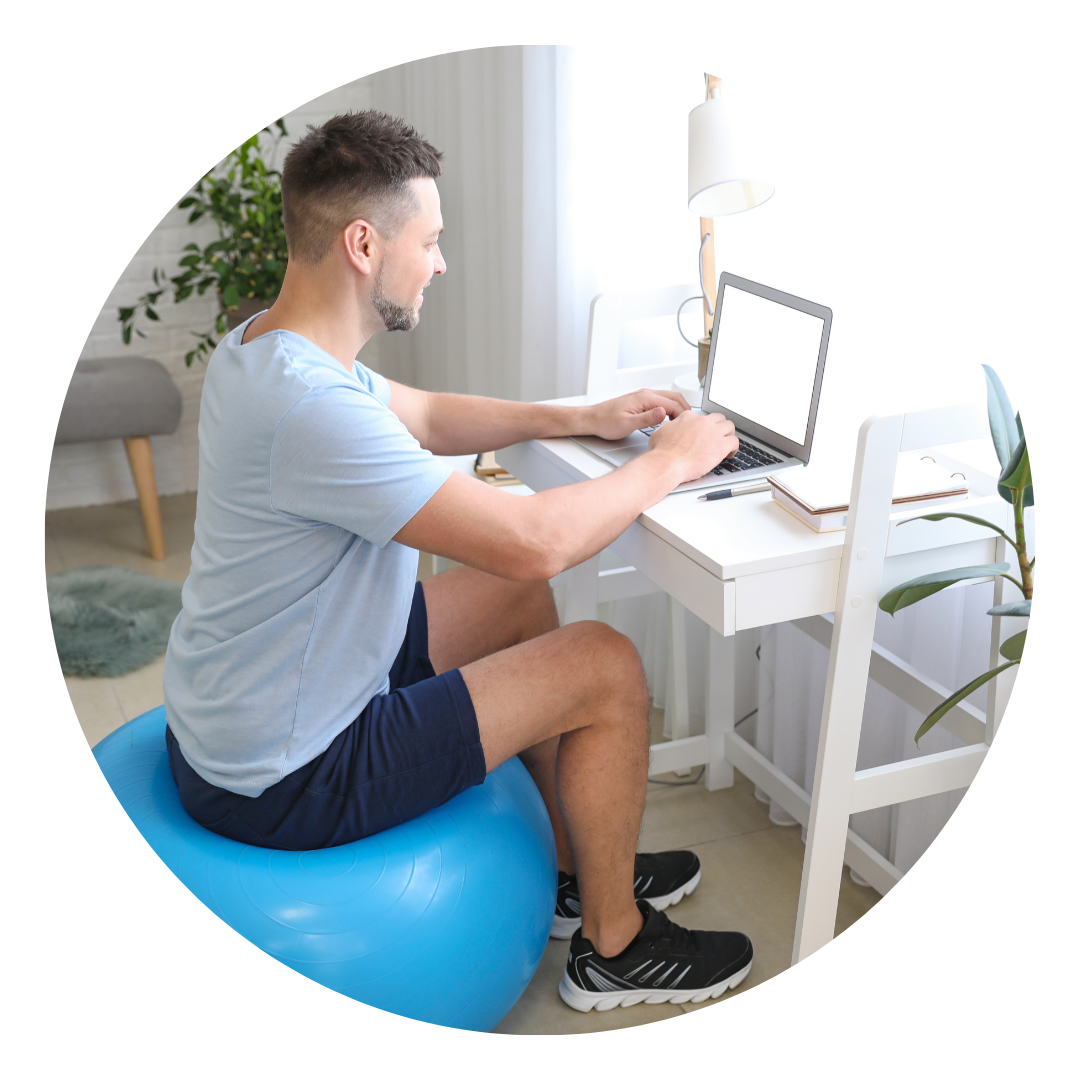 A man working on a laptop as he sits on an exercise ball.